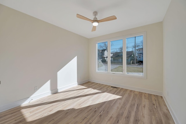 spare room with light wood-style floors, visible vents, baseboards, and a ceiling fan