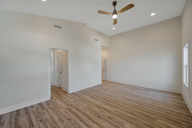 empty room featuring visible vents, vaulted ceiling, ceiling fan, light wood-type flooring, and baseboards