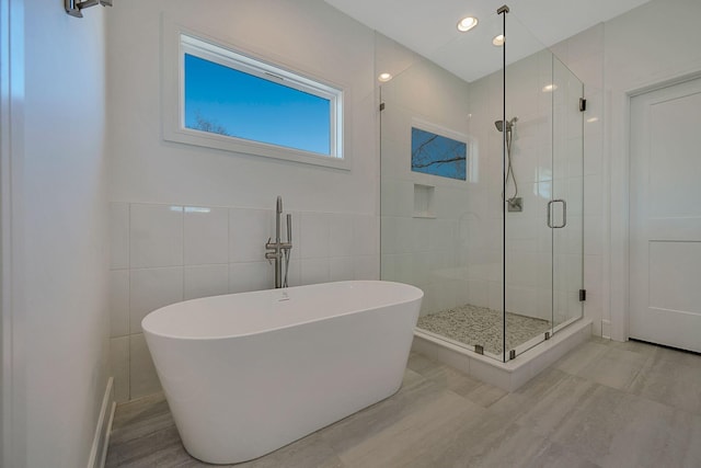 full bathroom with a stall shower, a freestanding tub, and tile walls