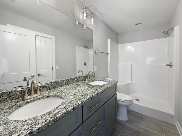 bathroom with walk in shower, vanity, and toilet