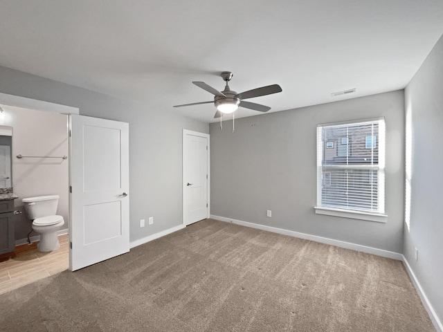 unfurnished bedroom with ensuite bathroom, carpet floors, and ceiling fan