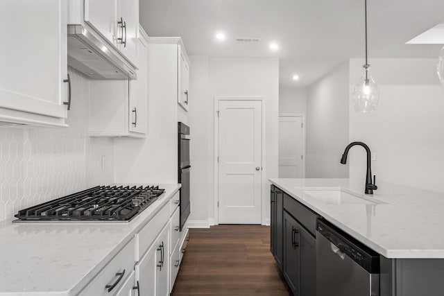 kitchen featuring appliances with stainless steel finishes, pendant lighting, white cabinetry, sink, and wall chimney range hood