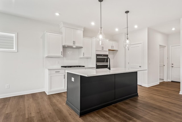 kitchen featuring gas stovetop, pendant lighting, a kitchen island with sink, and white cabinets