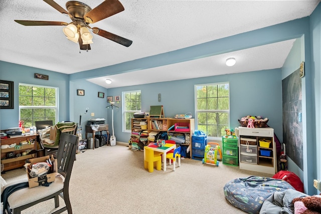 playroom with ceiling fan, a textured ceiling, and carpet flooring