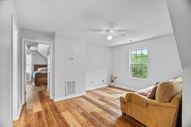 sitting room featuring ceiling fan, hardwood / wood-style floors, and a textured ceiling