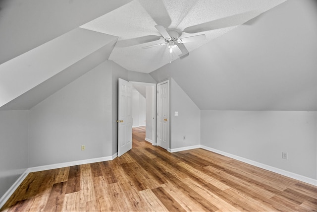 bonus room with lofted ceiling, a textured ceiling, wood-type flooring, and ceiling fan