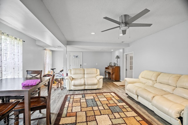 living room featuring ceiling fan, hardwood / wood-style floors, and a textured ceiling