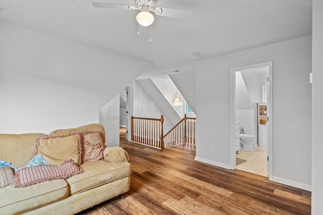 living room featuring ceiling fan, hardwood / wood-style floors, and a textured ceiling