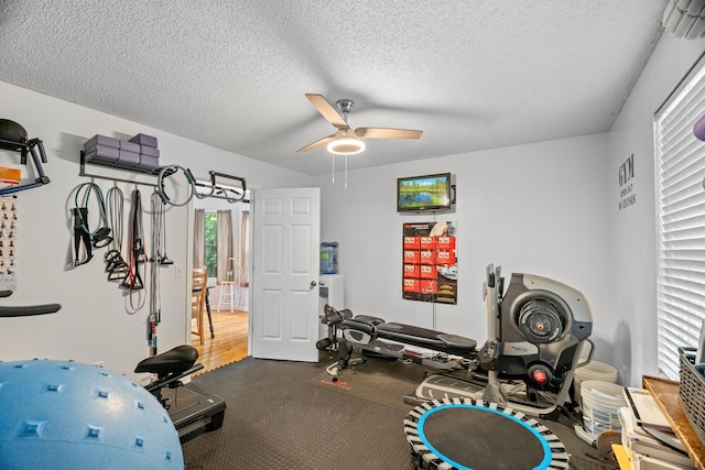 exercise room with ceiling fan and a textured ceiling