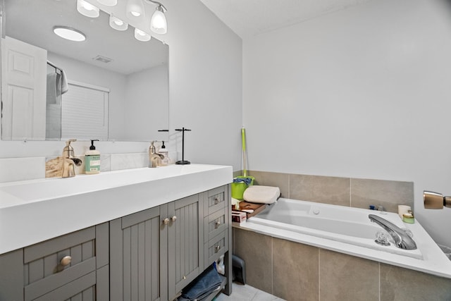 bathroom featuring a relaxing tiled tub, vanity, and tile patterned flooring