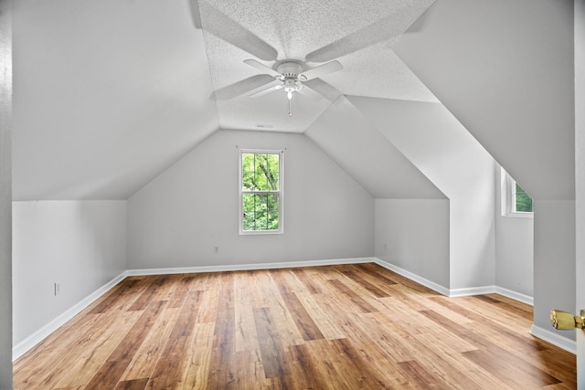 additional living space with ceiling fan, vaulted ceiling, light hardwood / wood-style flooring, and a textured ceiling