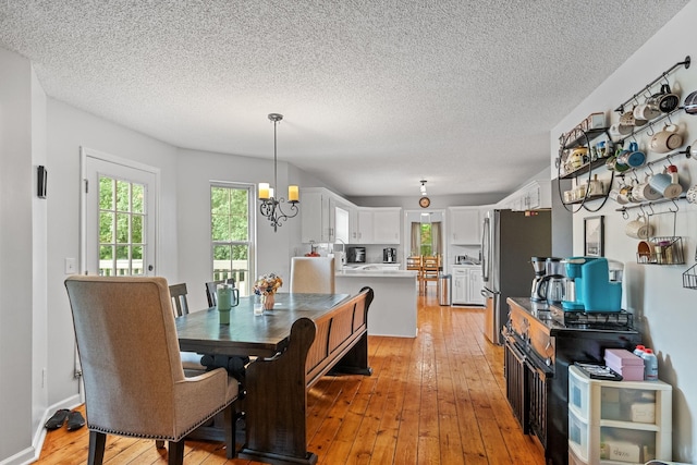 dining room featuring a notable chandelier, light hardwood / wood-style flooring, and a textured ceiling