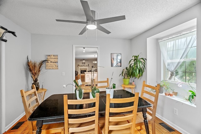 dining area with ceiling fan, hardwood / wood-style floors, and a textured ceiling