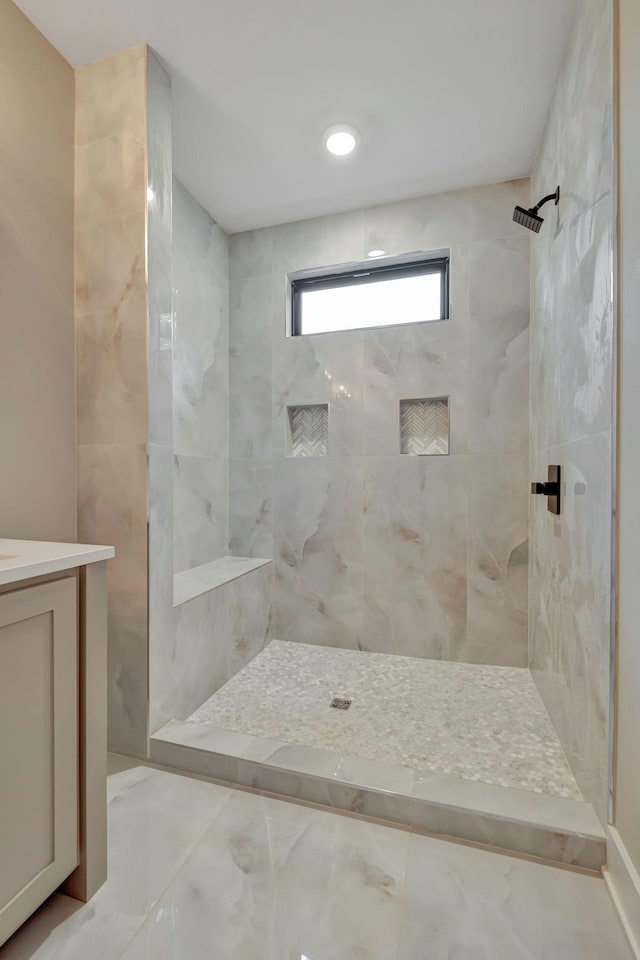 bathroom with vanity and a tile shower