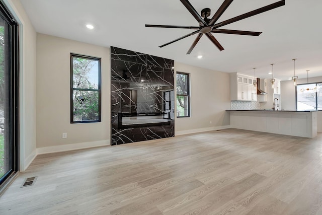 unfurnished living room featuring sink, light hardwood / wood-style flooring, and a healthy amount of sunlight