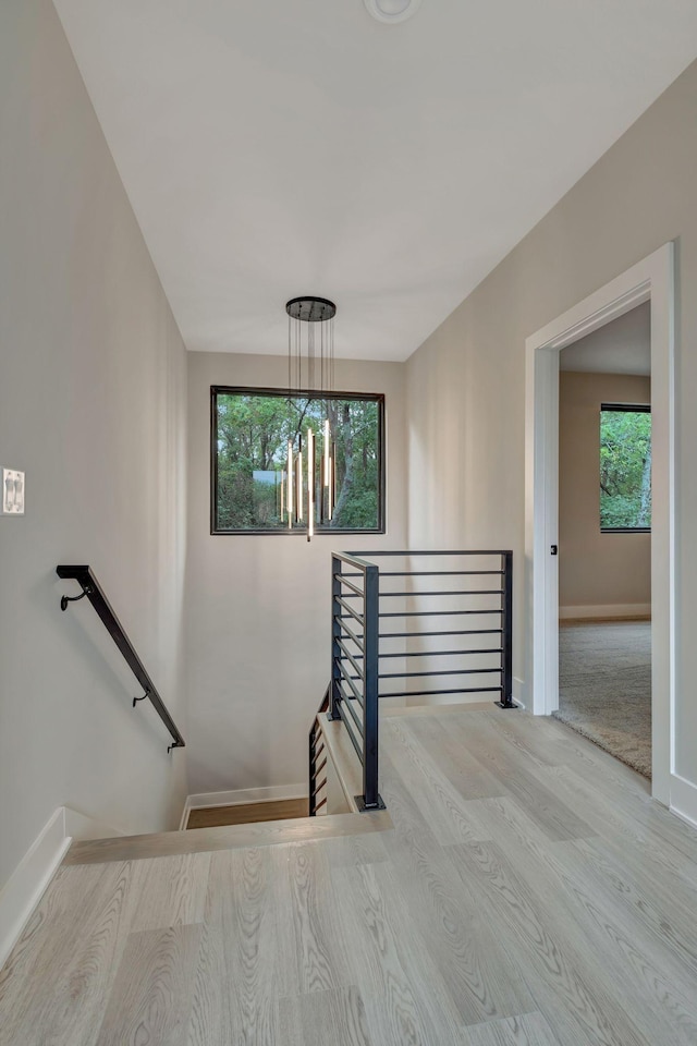 stairs with wood-type flooring and a chandelier