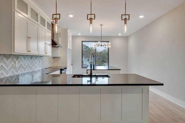 kitchen featuring sink, stainless steel range with electric cooktop, white cabinetry, decorative light fixtures, and backsplash