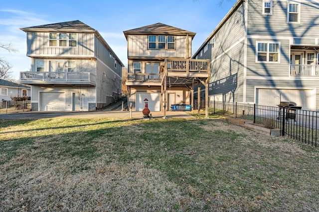 rear view of house with a garage, a balcony, a deck, and a lawn