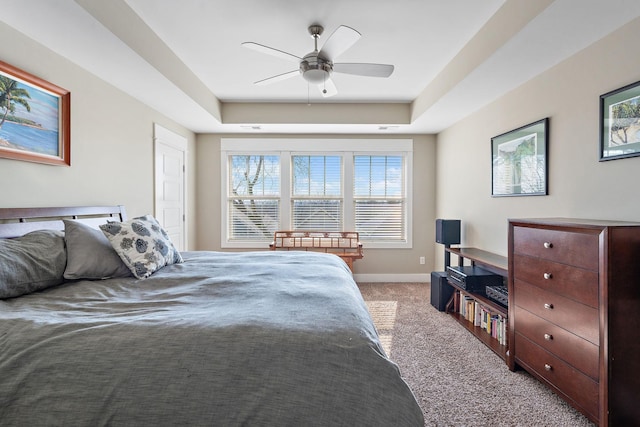 bedroom with a tray ceiling, light colored carpet, and ceiling fan