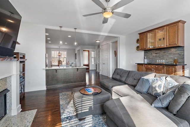 living room featuring dark wood-type flooring, ceiling fan, and a fireplace