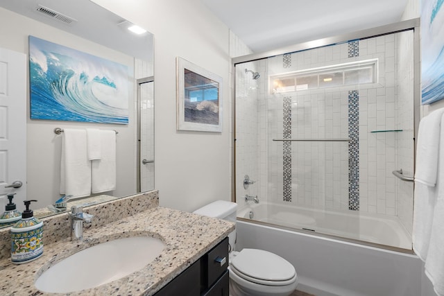 full bathroom with bath / shower combo with glass door, vanity, and toilet