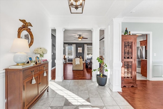 foyer featuring ceiling fan, ornamental molding, light tile patterned floors, and ornate columns