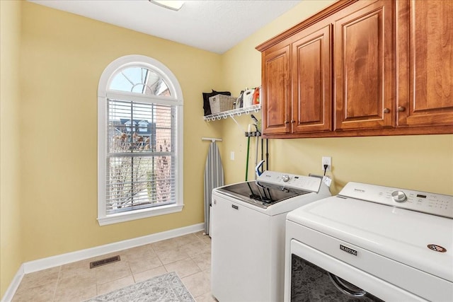 laundry area featuring light tile patterned floors, cabinets, and washing machine and clothes dryer