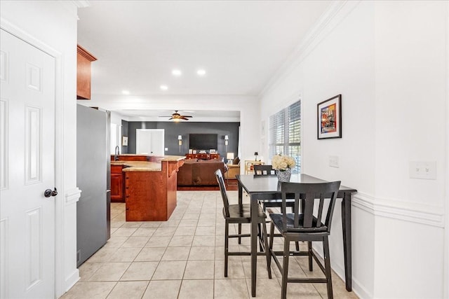 dining area featuring light tile patterned flooring, ceiling fan, ornamental molding, and sink