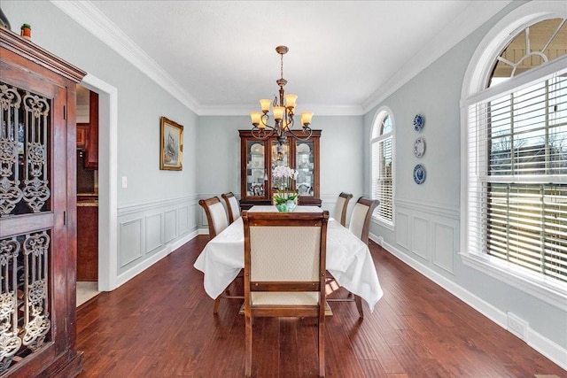 dining space with dark hardwood / wood-style flooring, crown molding, and a chandelier