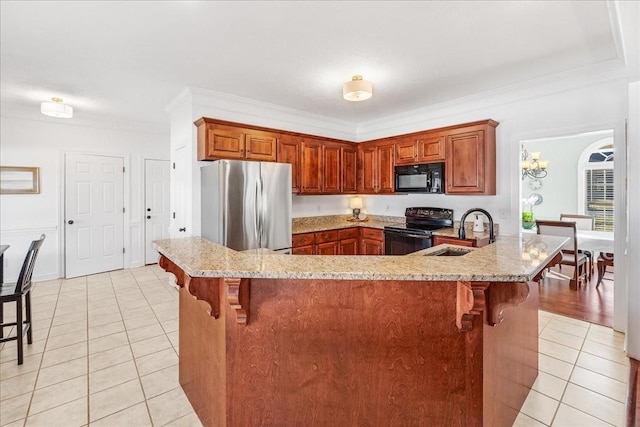 kitchen with sink, kitchen peninsula, a kitchen bar, and black appliances