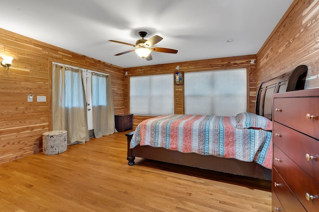 bedroom featuring multiple windows, wooden walls, and light hardwood / wood-style flooring