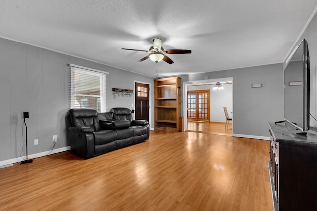 living room with crown molding, a textured ceiling, light hardwood / wood-style flooring, and ceiling fan