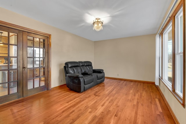 living area with french doors, light hardwood / wood-style floors, and a wealth of natural light