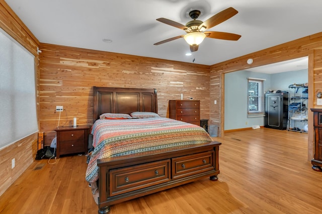 bedroom with ceiling fan, wooden walls, and light hardwood / wood-style floors