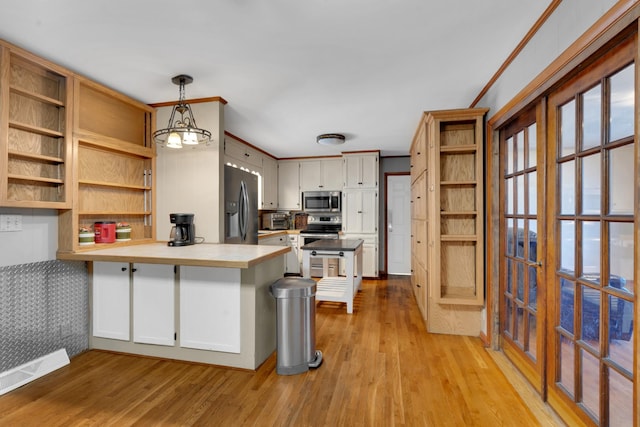 kitchen featuring decorative light fixtures, kitchen peninsula, white cabinets, and appliances with stainless steel finishes