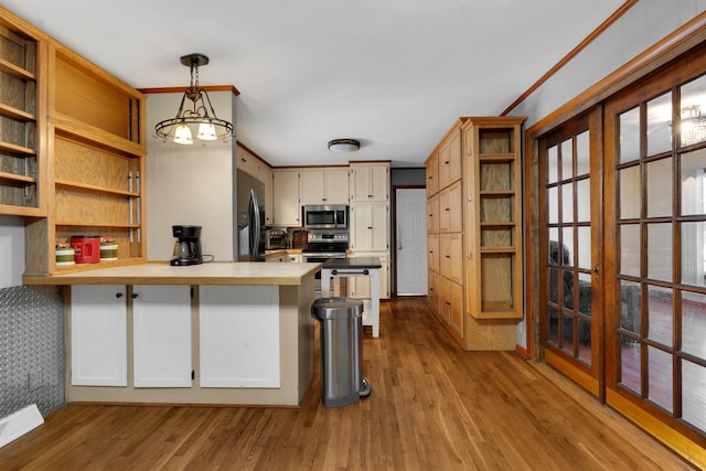 kitchen with appliances with stainless steel finishes, pendant lighting, ornamental molding, light hardwood / wood-style floors, and kitchen peninsula