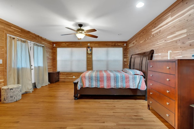 bedroom featuring wooden walls, light hardwood / wood-style floors, and ceiling fan