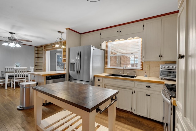 kitchen with hardwood / wood-style floors, stainless steel appliances, sink, and hanging light fixtures