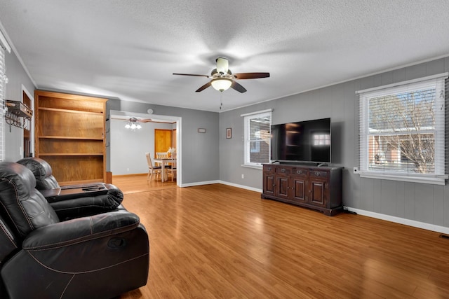 living room featuring wood-type flooring, ceiling fan, and a textured ceiling