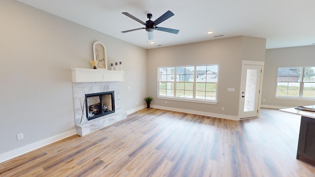 unfurnished living room featuring a fireplace, light hardwood / wood-style floors, and ceiling fan