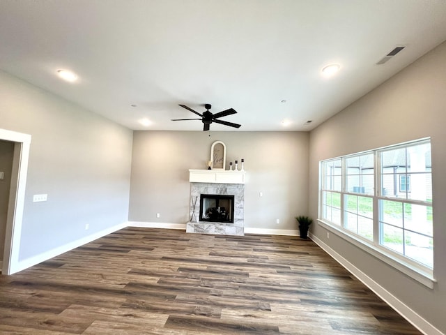 unfurnished living room with ceiling fan, a premium fireplace, and dark hardwood / wood-style flooring