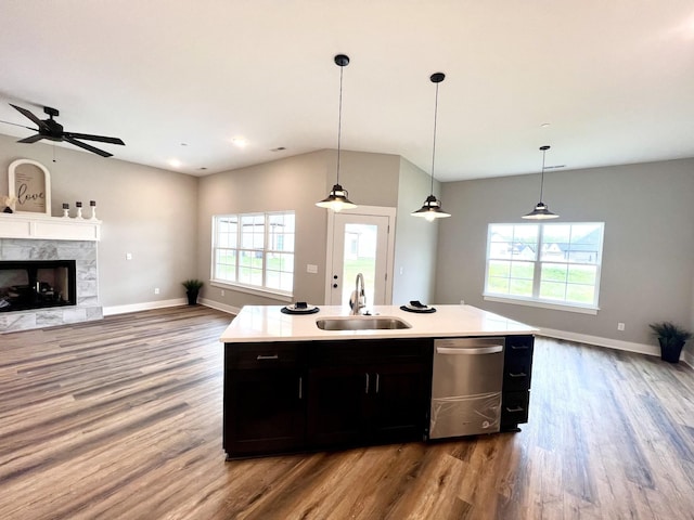 kitchen featuring a center island with sink, sink, pendant lighting, and a fireplace