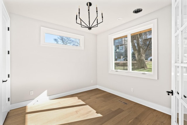 unfurnished room featuring hardwood / wood-style flooring and a chandelier