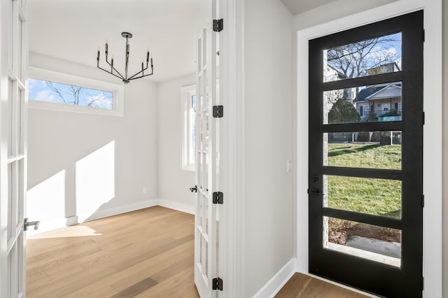 entrance foyer with a notable chandelier, light hardwood / wood-style flooring, and french doors