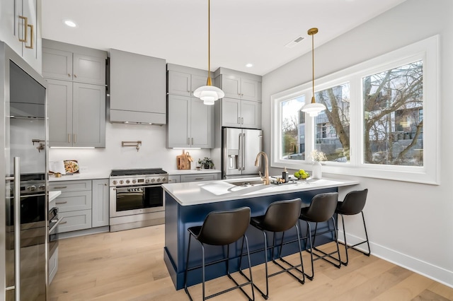 kitchen featuring pendant lighting, sink, a kitchen breakfast bar, stainless steel appliances, and light wood-type flooring