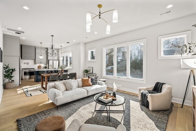 living room featuring a notable chandelier and light wood-type flooring