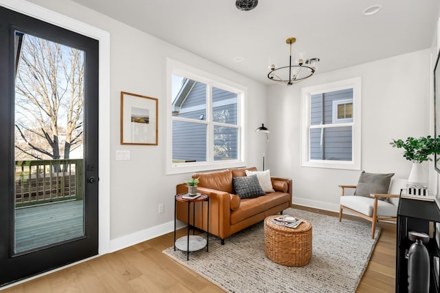 sitting room with an inviting chandelier, plenty of natural light, and light wood-type flooring