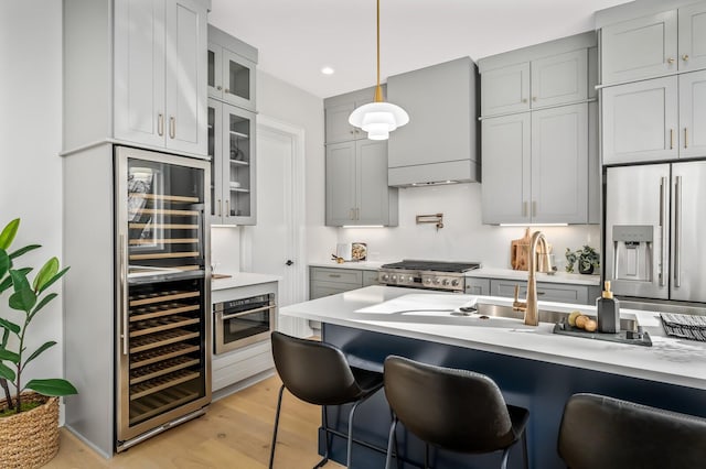 kitchen featuring wall chimney exhaust hood, stainless steel appliances, a kitchen bar, and wine cooler