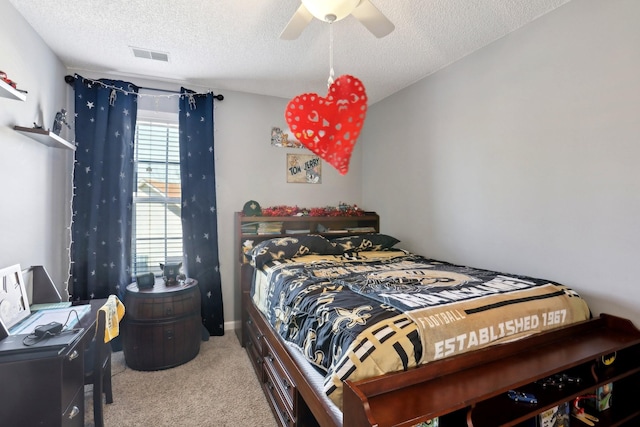 carpeted bedroom with ceiling fan and a textured ceiling