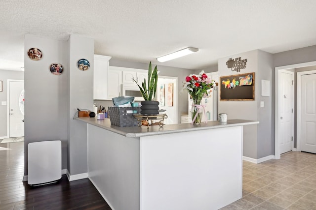 kitchen featuring white cabinetry, kitchen peninsula, and a textured ceiling